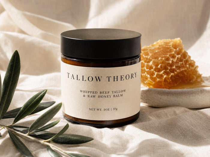 Tallow Theory Whipped Beef Tallow & Raw Honey Balm amber jar with cream label on linen with honeycomb and olive branch